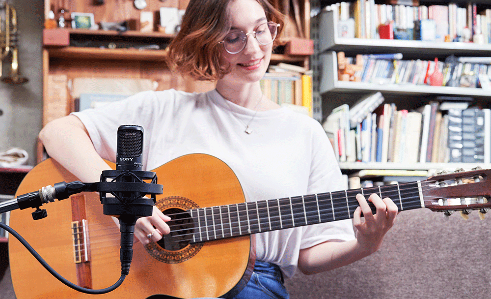 여자 모델이 기타를 치고 있고 소니 C-80 제품으로 레코딩을 하고 있는 모습의 사진입니다.